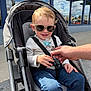 Jackson joined the competition — help win amazing prizes! child, toddler, sunglasses, stroller, pacifier, hand, jeans, long_sleeve, smile, urban, sidewalk, window, reflection, daylight, casual, outdoor, person, baby, seatbelt, building