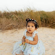 Aria joined the competition — help win amazing prizes! child, toddler, baby, dress, floral_dress, beach, sand, dunes, grass, sitting, barefoot, hair_bows, bracelets, curious_expression, portrait, outdoor, candid, cute, sunshine, hands