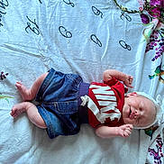Bailee is registered to the contest to win money with this photo: baby, infant, child, smiling, clothing, red_shirt, denim_shorts, headband, blanket, floral_pattern, bottle, sleeping, happy, cute, lying_down, indoors, person, baby_bottle, fabric, soft_texture
