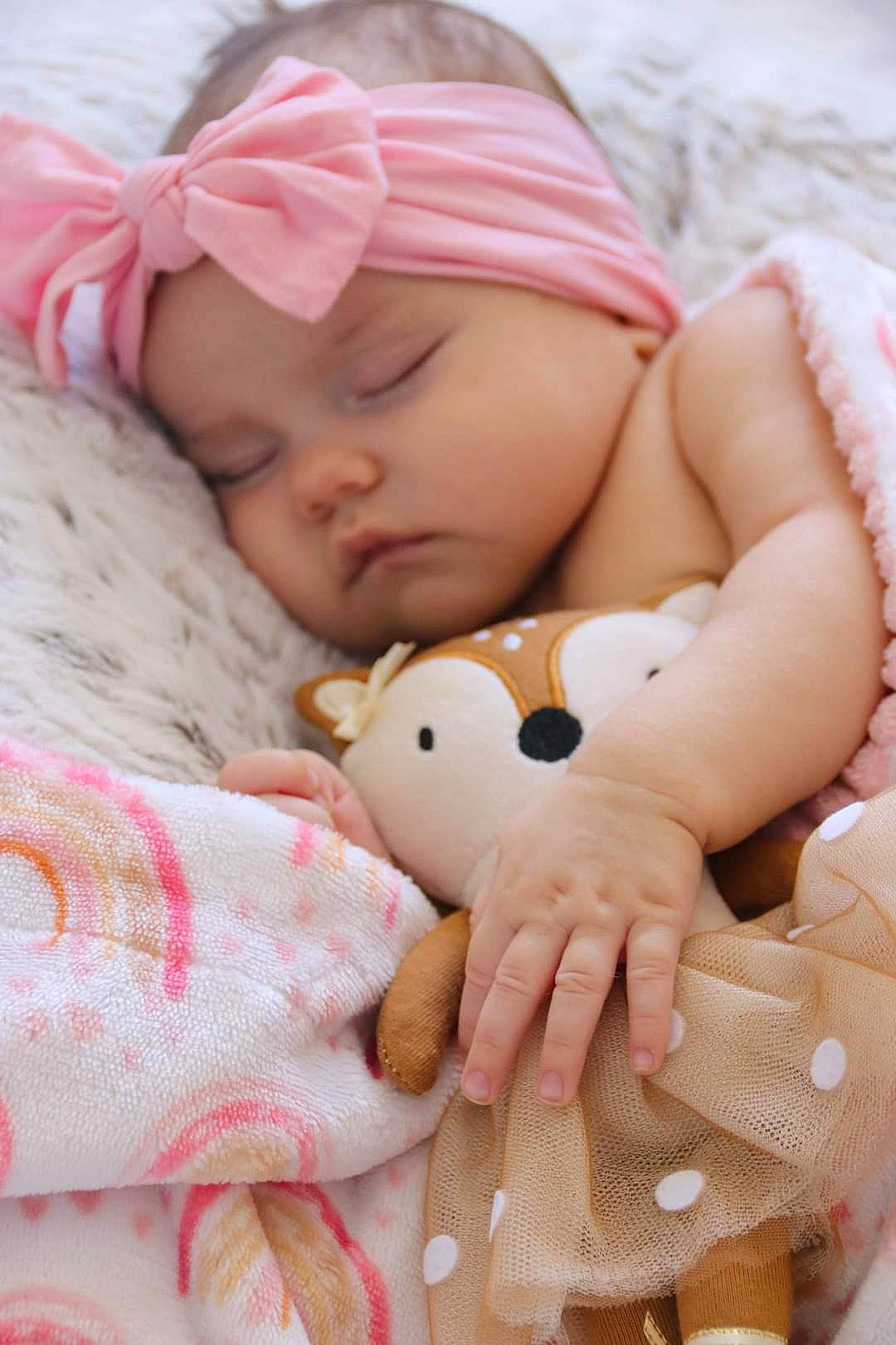 Sophie joined the competition — help win amazing prizes! baby, baby_sleeping, baby_toddler_clothing, bed, bedding, child, comfort, finger, hand, happy, headwear, linens, nail, pattern, person, pink, skin, textile, toddler, toy