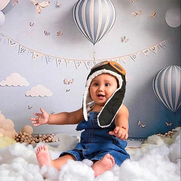 Iván Gabriel joined the competition — help win amazing prizes! baby, child, denim_overalls, aviator_hat, smiling, sitting, clouds, hot_air_balloon, indoor, decorative_bunting, butterflies, soft_toys, pastel_colors, cute, portrait, happy, toddler, playful, nursery, cozy