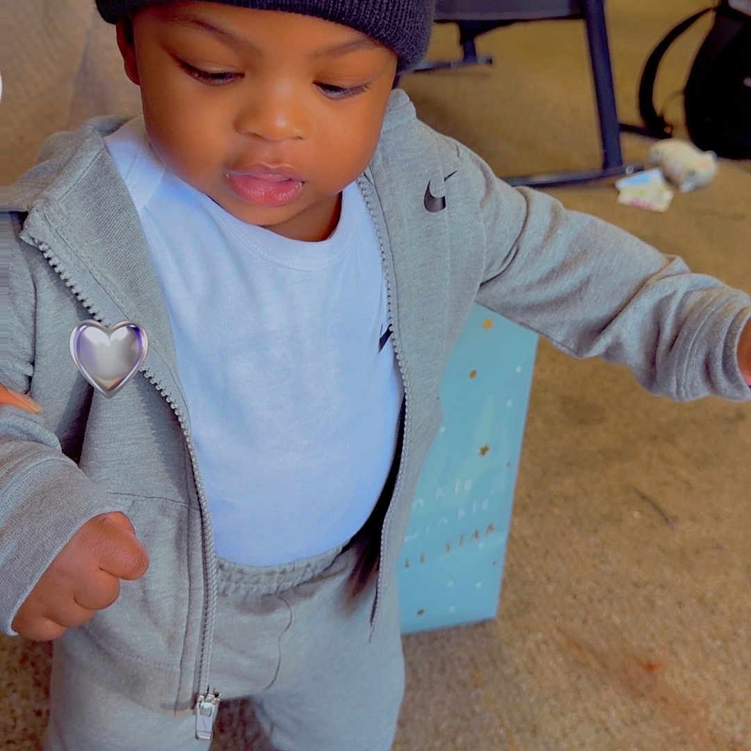 Consta joined the competition — help win amazing prizes! child, toddler, portrait, standing, indoors, beanie, heart, tracksuit, hoodie, sneakers, gray_clothing, fashion, streetwear, looking_down, serious_expression, carpet, chair, toys, living_room, full_body