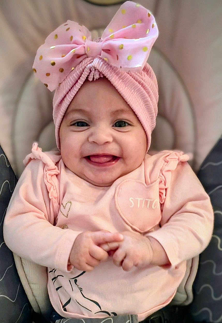 Sophia participe au concours pour gagner de l'argent avec cette photo : baby, child, smile, pink_bow, headwear, pink_clothing, cute, happy, infant, portrait, seated, hands, face, tongue, cheerful, cushion, indoor, closeup, apparel, adorable