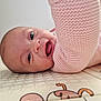 baby, infant, smiling, pink_sweater, knitted, lying_down, play_mat, happy, face, child, cute, indoor, closeup, person, skin, eyes, mouth, expression, baby_girl, cozy