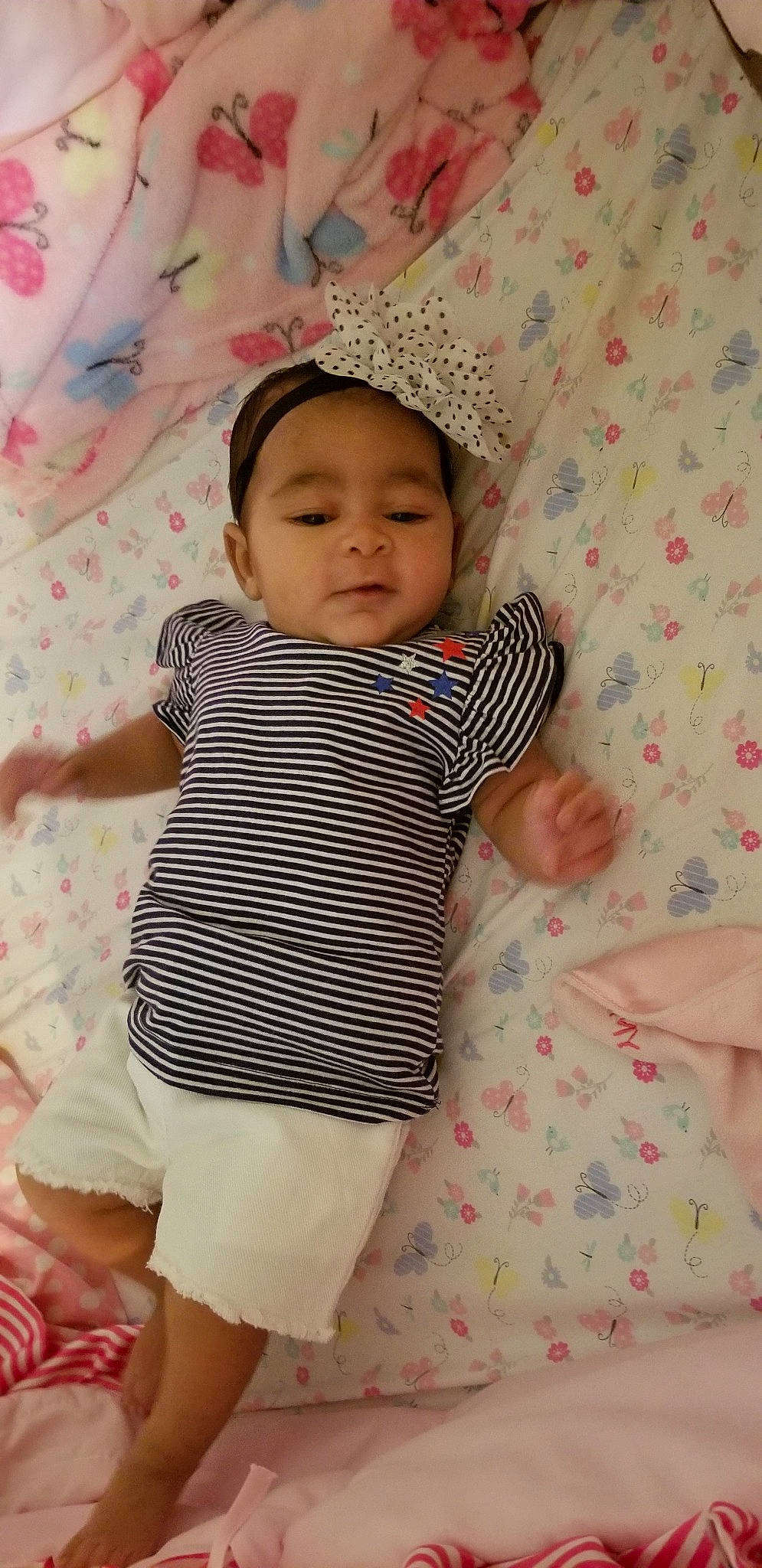 Davina is registered to the contest to win money with this photo: abdomen, baby_products, beauty, cheek, child, day, eye, girl, hair_accessory, headgear, infant, iris, leg, person, pink, product, sitting, skin, smile, textile