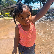 Aaliyah joined the competition — help win amazing prizes! child, toddler, water, splash_pad, outdoor, sunny, daylight, swimsuit, denim_shorts, water_spray, play, curly_hair, nature, trees, blue_sky, summer, cute, person, fun, park