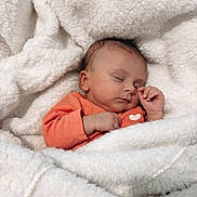 Luna participe au concours pour gagner de l'argent avec cette photo : baby, sleeping, blanket, orange_clothing, infant, cozy, soft_texture, peaceful, cute, newborn, wrapped, hand, face, portrait, resting, indoor, warm, comfort, closeup, child