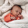 baby, newborn, sleeping, blanket, orange_clothing, infant, cozy, cute, peaceful, face, hand, soft_texture, warm, resting, portrait, child, wrapped, indoors, toddler, heart