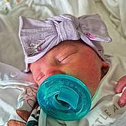 Paisley joined the competition — help win amazing prizes! baby, bedding, blanket, bow, closed_eyes, closeup, clothing, cozy, face, hand, headband, hospital, indoors, infant, newborn, pacifier, portrait, sleeping, swaddled, textile