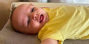 Jahlënn a rejoint le concours — aidez-le/la à gagner de superbes lots ! baby, child, yellow_shirt, smiling, lying_down, towel, indoor, happy, face, skin, arm, head, infant, cute, young, person, expression, casual, relaxed, closeup