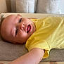 baby, child, yellow_shirt, smiling, lying_down, towel, indoor, happy, face, skin, arm, head, infant, cute, young, person, expression, casual, relaxed, closeup