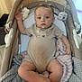 baby, infant, onesie, bear_design, baby_carrier, blanket, plush_toy, face, child, indoors, soft_toys, cute, comfort, resting, expression, clothing, legs, arms, head, floor