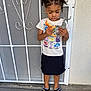 child, toy, dinosaur, elephant, tshirt, skirt, slippers, standing, concrete, gate, metal, emotion, cartoon, outdoor, person, hair, play, young, casual, curly_hair