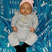 La'Ilah joined the competition — help win amazing prizes! baby, infant, sleeping, headband, bow, onesie, text_on_clothing, blanket, blue_blanket, lying_down, closed_eyes, peaceful, cute, chubby_cheeks, tiny_hands, black_socks, cozy, portrait, soft_texture, newborn