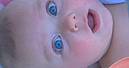 Ryder is registered to the contest to win money with this photo: baby, child, infant, face, portrait, blue_eyes, wide_eyed, lying_down, close_up, indoors, blanket, colorful, pink_container, soft_lighting, blonde_hair, open_mouth, curious, nursery, candid, photography