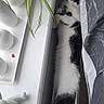 cat, black_and_white, stretching, bed, plant, windowsill, indoor, cozy, curious, feline, relaxed, houseplant, decor, white, black, fur, pet, resting, narrow_space, home