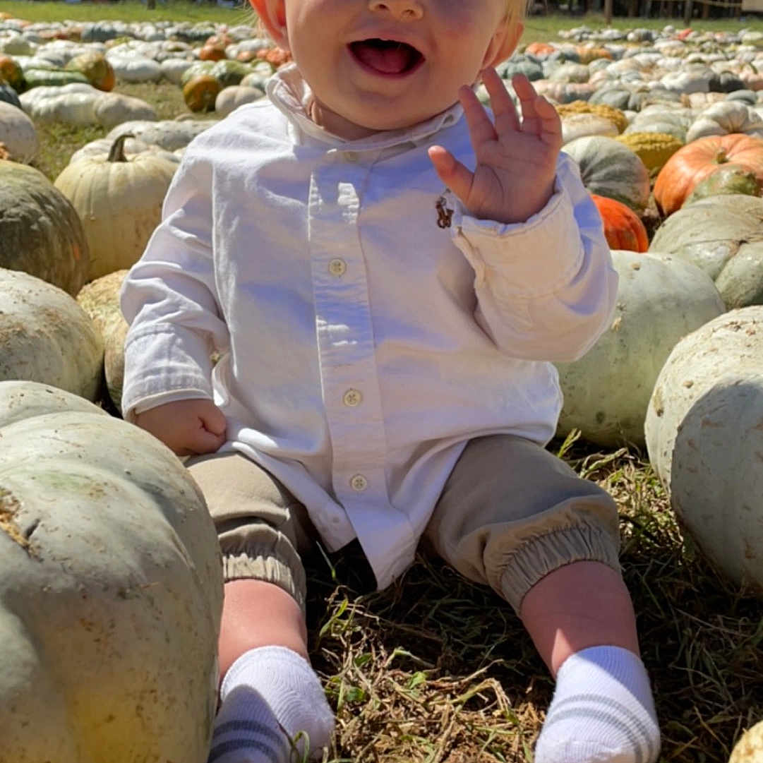 Niklaus is registered to the contest to win money with this photo: baby, clothing, face, food, grass, head, herbal, herbs, hosiery, outdoors, pants, person, photography, plant, portrait, produce, pumpkin, sock, squash, vegetable