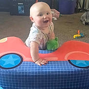 Ivana is registered to the contest to win money with this photo: baby, car_toy, carpet, child, colorful, crawling, cute, furniture, happy, indoor, infant, living_room, person, play, playtime, plush_toy, smiling, storage_bin, table, toy