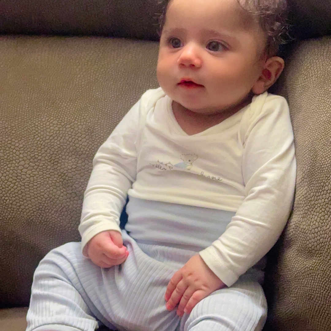 Avitaaj Singh joined the competition — help win amazing prizes! baby, barefoot, blue_pants, child, clothing, comfort, couch, curly_hair, cute, face, feet, furniture, hands, indoors, infant, portrait, sitting, skin, white_shirt, young_child