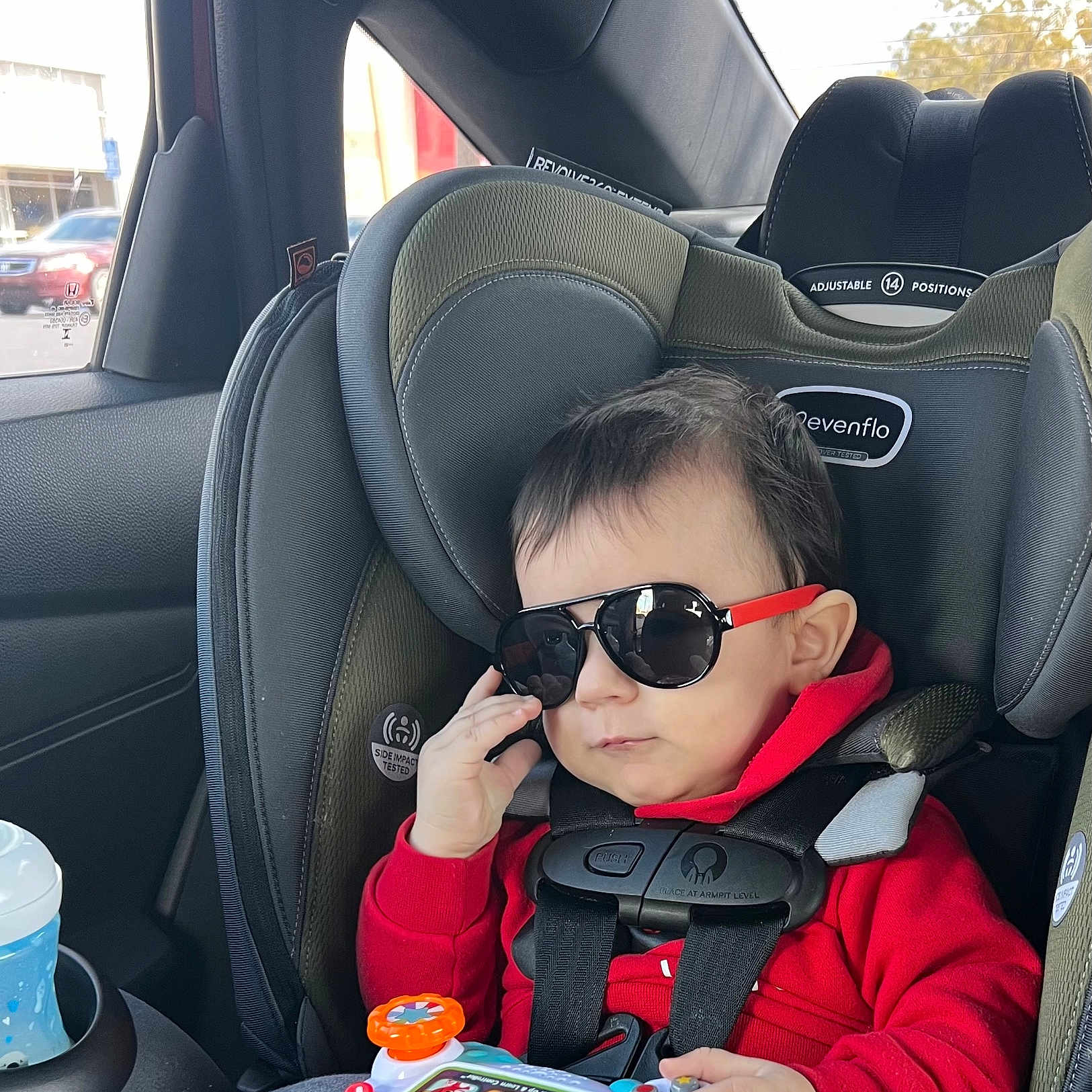 Ace is registered to the contest to win money with this photo: accessories, baby, car, car_interior, carseat, cushion, eating, face, food, hair, head, headrest, homedecor, person, photography, portrait, sitting, sunglasses, transportation, vehicle