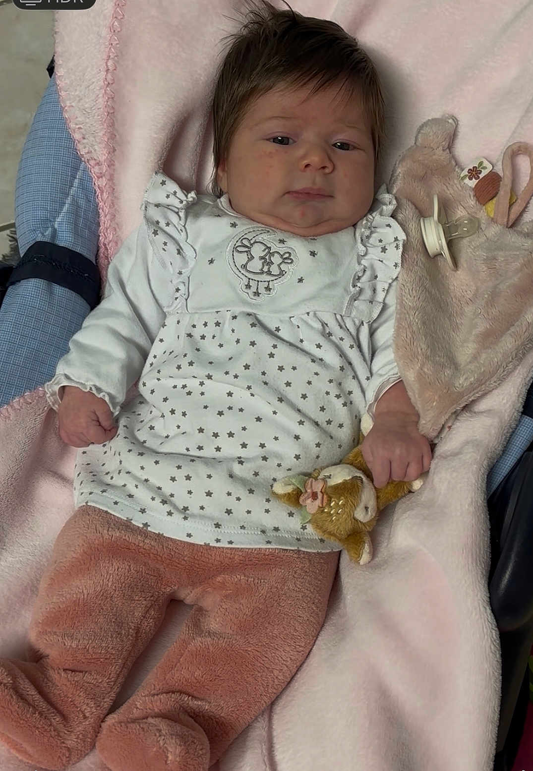Yara participe au concours pour gagner de l'argent avec cette photo : baby, infant, blanket, plush_toy, pacifier, clothing, pink, white, star_pattern, soft_texture, cute, child, portrait, indoors, lying_down, young_child, face, hand, footwear, fabric