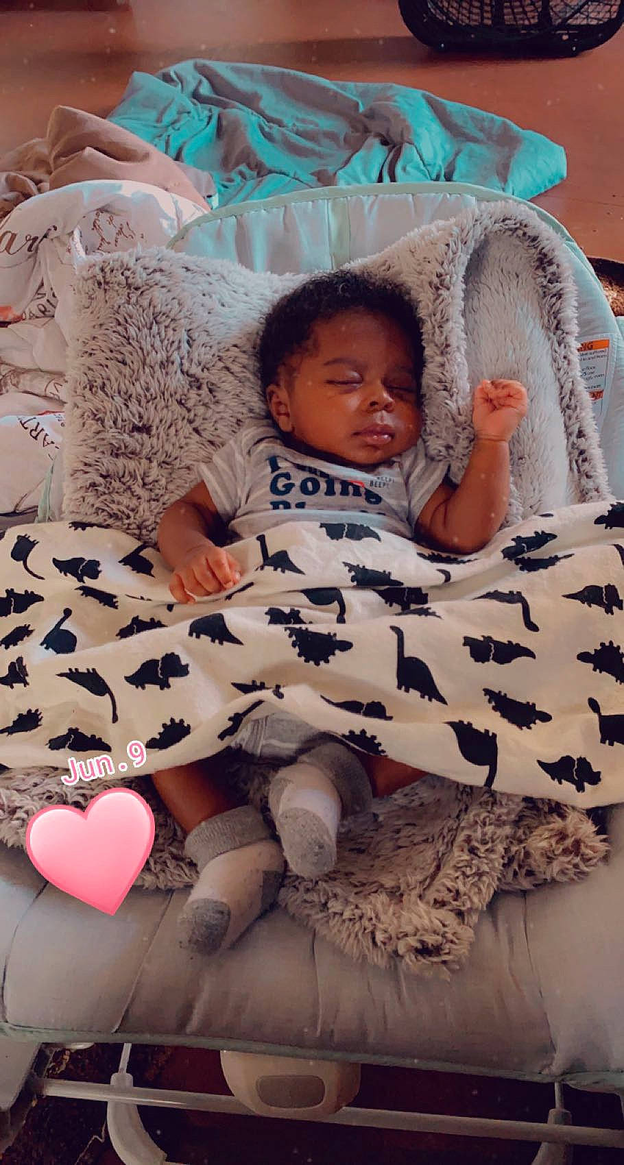 Legend is registered to the contest to win money with this photo: baby, bedding, child, comfort, finger, hairstyle, happy, human_leg, linens, magenta, mouth, pattern, person, pink, sitting, skin, sleeve, textile, thigh, toddler