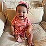 baby, child, smile, pink_headband, striped_dress, couch, cushion, indoor, happy, sitting, cute, infant, small_toes, hand, portrait, person, comfortable, soft_furniture, home, bright
