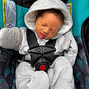 Elliot is registered to the contest to win money with this photo: baby, infant, child, car_seat, onesie, hood, tongue_out, straps, cozy, sleepy, cute, seatbelt, patterned, fabric, small_person, portrait, indoors, soft_texture, wrapped, secure