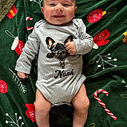 Noah a rejoint le concours — aidez-le/la à gagner de superbes lots ! baby, infant, smiling, onesie, dog_graphic, holiday_blanket, candy_cane, mittens, bare_feet, lying_down, cute, joyful, festive, child, person, indoors, blanket, clothing, portrait, happy