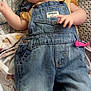 Adelynn is registered to the contest to win money with this photo: baby, smiling, denim_overalls, yellow_shirt, bed, blanket, infant, cute, happy, person, clothing, child, face, hand, pink_clip, fabric, pattern, portrait, lying_down, cozy