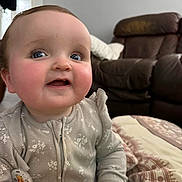 Emily Rose joined the competition — help win amazing prizes! architecture, baby, babylaughing, building, clothing, coat, couch, face, furniture, happy, head, indoors, jacket, livingroom, person, photography, portrait, room, sitting, smile