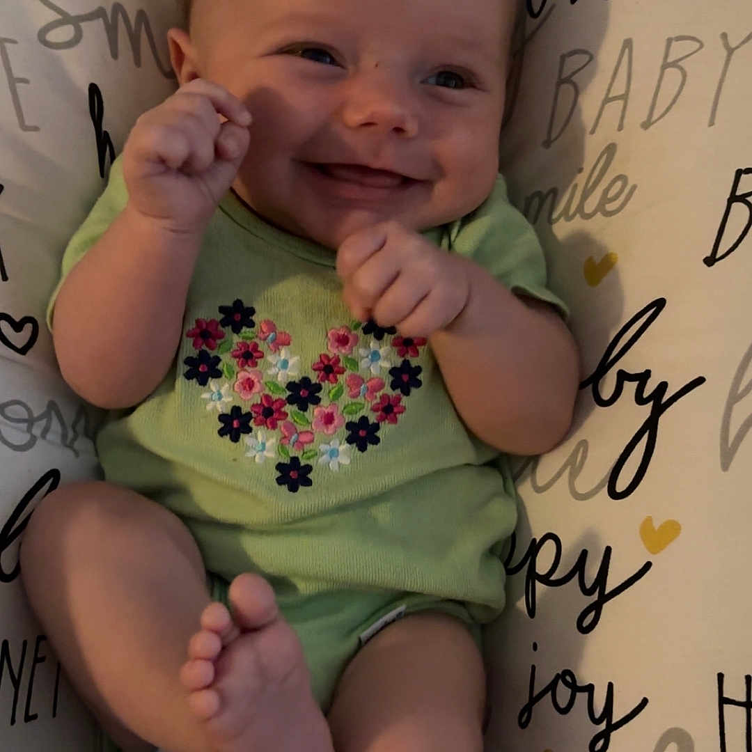 Karsyn Renee Horton joined the competition — help win amazing prizes! baby, blanket, child, cushion, cute, face, floral_pattern, foot, green_onesie, hand, happy, indoors, infant, joy, love, playful, portrait, smiling, soft_toy, text_background