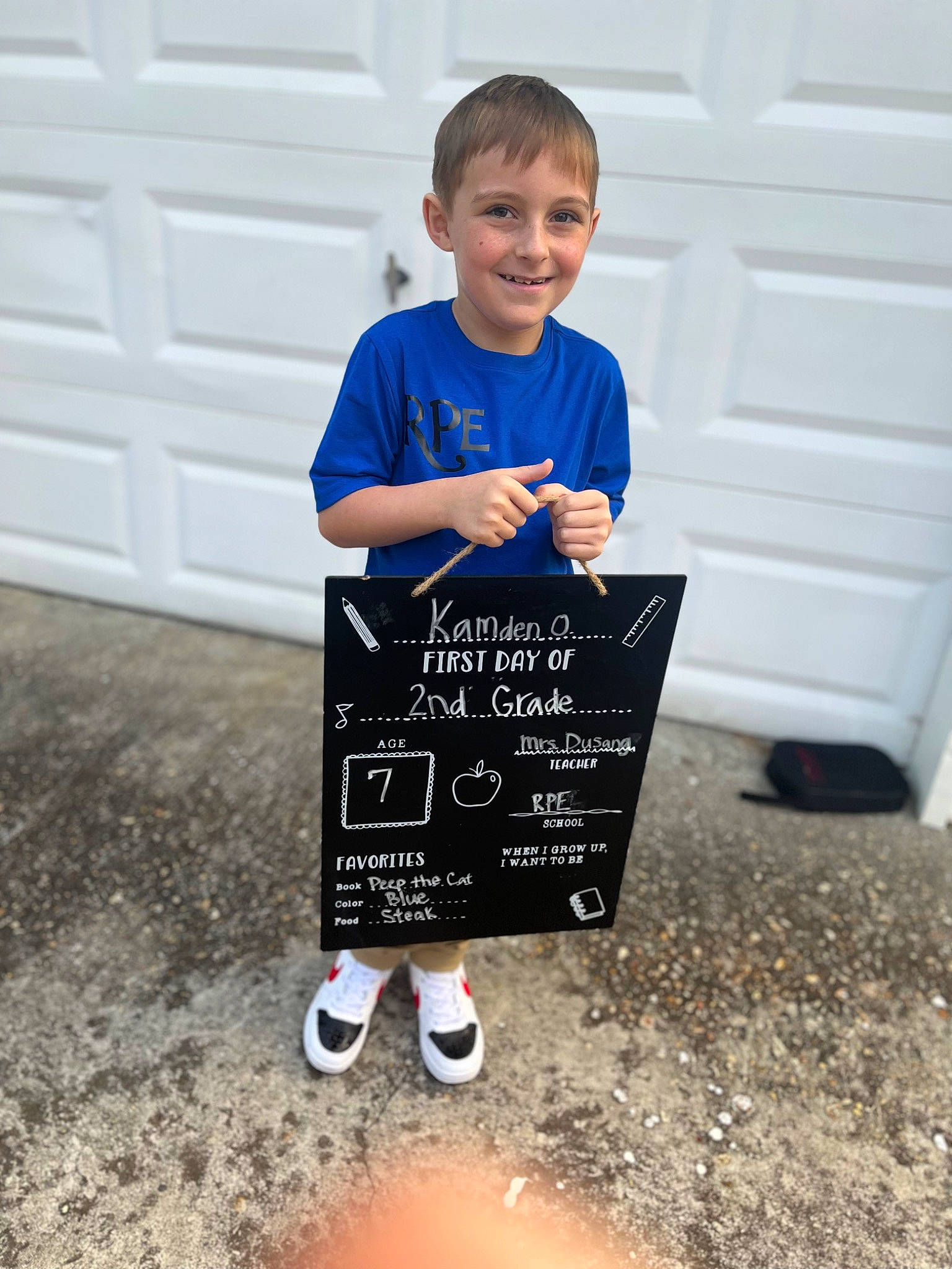 Kamden is registered to the contest to win money with this photo: child, door, electric_blue, finger, flooring, font, fun, grass, hand, handwriting, happy, joy, leisure, person, recreation, sitting, sleeve, smile, soil, t_shirt