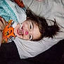Oktavia is registered to the contest to win money with this photo: child, face_paint, smile, pajamas, bed, blanket, happy, lying_down, cozy, indoor, hair, freckles, orange_clothing, cute, portrait, resting, fun, nighttime, playful, person