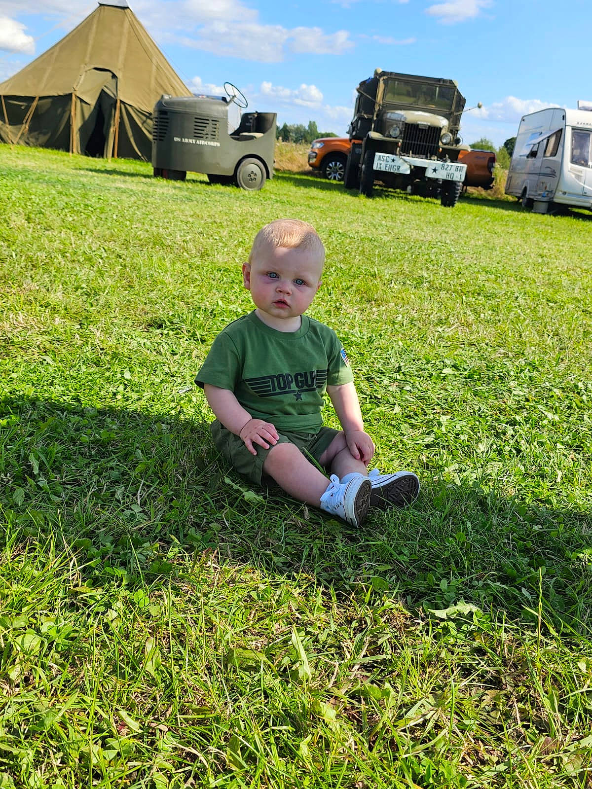 Arthur is registered to the contest to win money with this photo: automotive_tire, car, cloud, grass, grass_family, grassland, groundcover, hat, meadow, natural_environment, people_in_nature, person, shorts, sky, summer, tent, tire, toddler, truck, vehicle