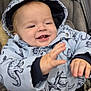 baby, child, smiling, dinosaur_pattern, jacket, hood, stroller, clothing, happy, cute, infant, face, hand, seatbelt, cozy, warm, outdoor, portrait, closeup, fun