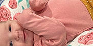 Luciana joined the competition — help win amazing prizes! baby, infant, pink_clothing, smile, face, blue_eyes, blanket, floral_pattern, soft_texture, lying_down, cute, child, cozy, sleepwear, portrait, closeup, skin, resting, indoors, comfort