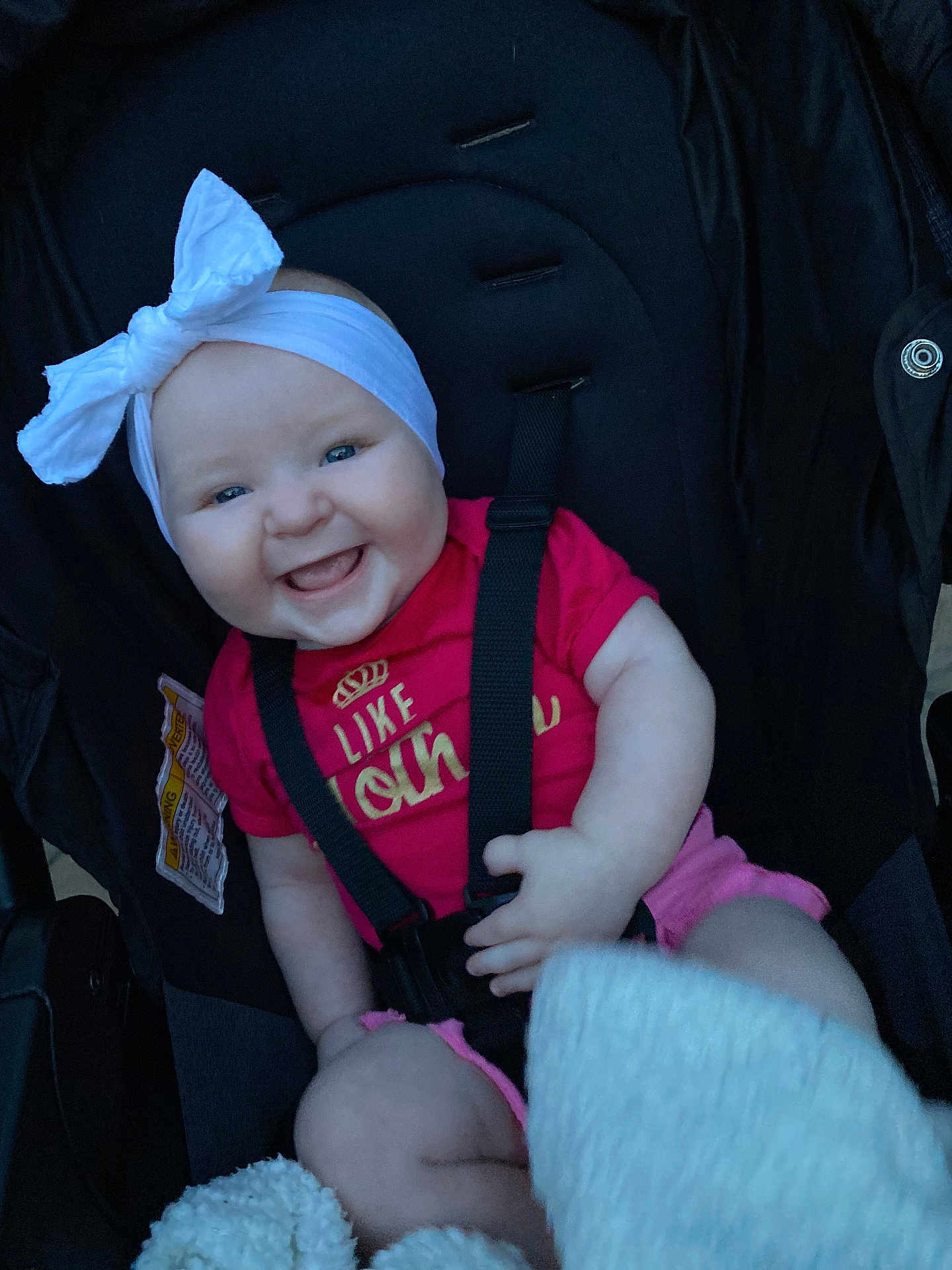 Luciana is registered to the contest to win money with this photo: baby, smiling, headband, bow, stroller, child, happy, infant, clothing, pink, white, cute, sitting, strap, seatbelt, person, portrait, young, joyful, face