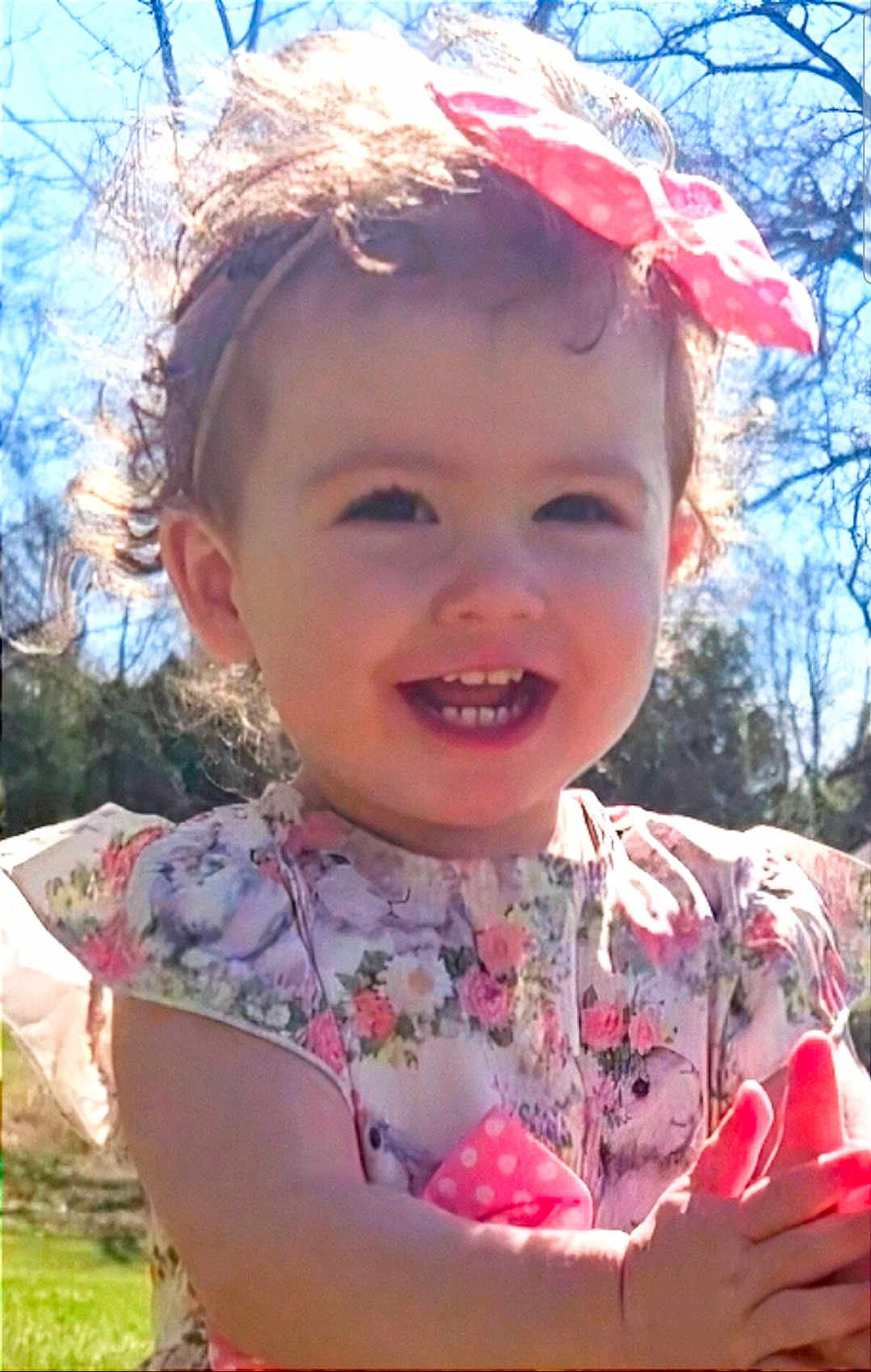 Michelle Shelly joined the competition — help win amazing prizes! toddler, child, smiling, outdoor, sunlight, bow, curly_hair, floral_dress, clapping, happy, portrait, nature, trees, blue_sky, cute, baby, person, daylight, spring, innocence