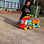 Nazir joined the competition — help win amazing prizes! toddler, child, hoodie, toy_train, outdoor, playtime, concrete, sunlight, smiling, black_clothing, wheels, plastic_toy, garden, ladder, trash_bin, sidewalk, daytime, person, casual, happy