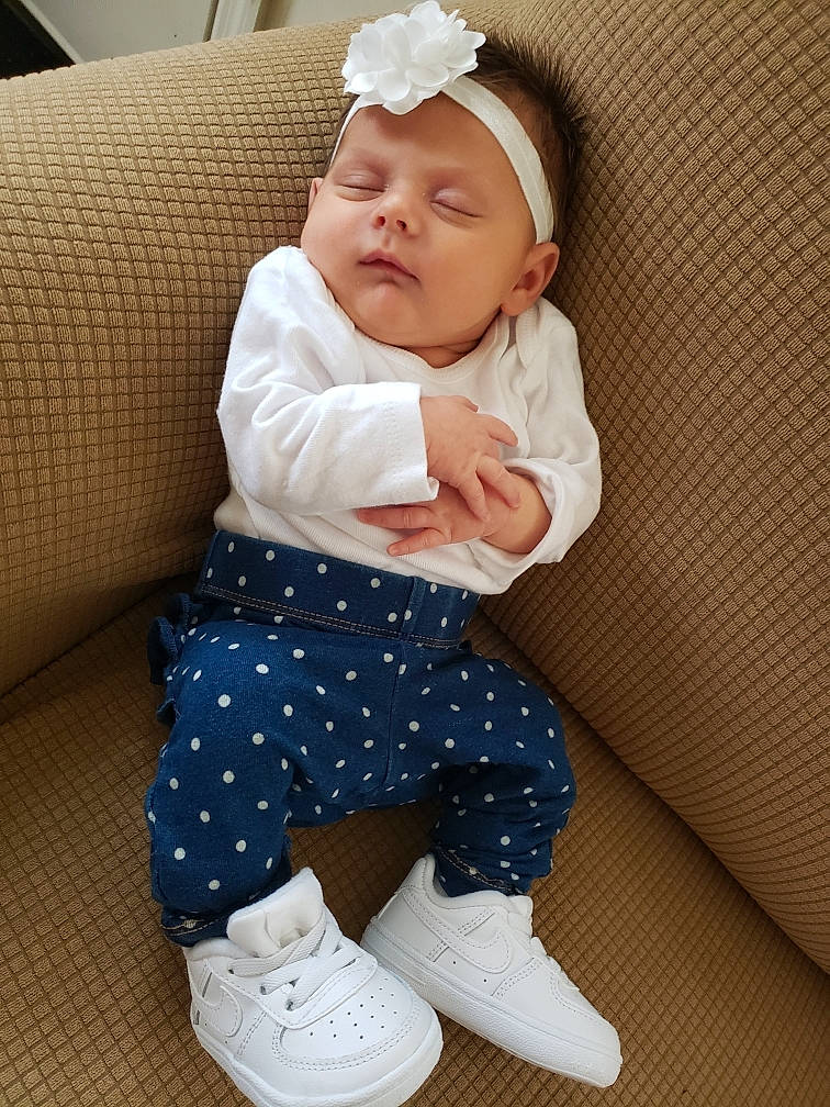 Jazmin is registered to the contest to win money with this photo: arm, baby, baby_toddler_clothing, cap, child, comfort, face, fashion_accessory, foot, hairstyle, headwear, human_leg, knee, pattern, person, skin, sleeve, sock, textile, thigh