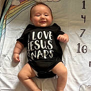 Asher is registered to the contest to win money with this photo: baby, infant, smiling, onesie, black_clothing, rainbow, clouds, blanket, milestone, numbers, cute, happy, lying_down, child, skin, head, arms, legs, indoors, portrait