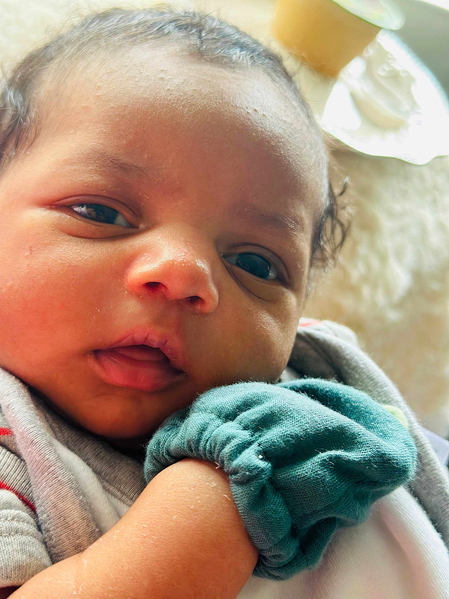 Kaysen joined the competition — help win amazing prizes! baby, face, closeup, infant, skin, clothing, mitten, hand, expression, portrait, cute, young_child, soft_lighting, indoors, person, head, eyes, mouth, newborn, warm_tones