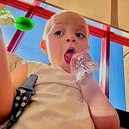 Pablo joined the competition — help win amazing prizes! child, lollipop, candy, indoors, window, red_frame, blue_sky, face, happy, cute, closeup, person, sleeveless_shirt, daylight, hand, expression, young_child, bright, fun, snack