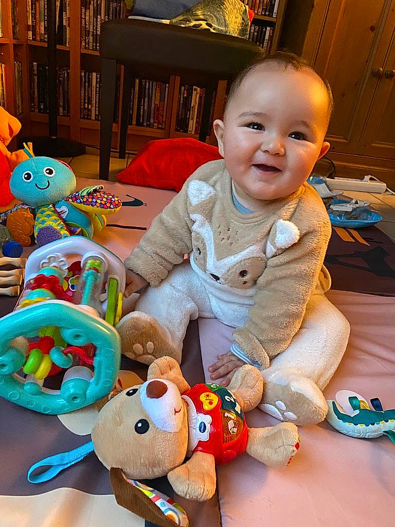 Harry participe au concours pour gagner de l'argent avec cette photo : baby, baby_toddler_clothing, cheek, child, event, facial_expression, flooring, fun, happy, head, joy, organ, people, person, photograph, sitting, smile, snapshot, stuffed_toy, textile