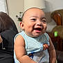 Anthony is registered to the contest to win money with this photo: baby, smiling, dimples, blanket, arm, tattoo, person, indoor, living_room, lamp, couch, portrait, happy, child, clothing, holding, skin, furniture, hand, face