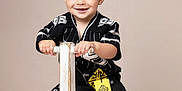 Ean joined the competition — help win amazing prizes! toddler, child, smiling, ride_on_toy, wooden_toy, black_clothing, pants, shoes, studio_photo, beige_background, happy, face, hands, short_hair, sitting, cute, fashion, portrait, indoor, play