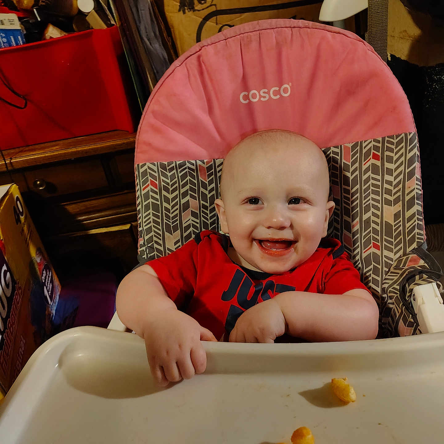 Zaidyn is registered to the contest to win money with this photo: baby, high_chair, smiling, snack, food, indoor, child, pink, red_shirt, face, happy, furniture, table, tray, clutter, storage, expression, cute, person, young