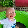 Zaidyn joined the competition — help win amazing prizes! toddler, child, smiling, happy, baby, face, inflatable_ring, green, outdoor, plants, leaves, wooden_floor, red_cushion, wicker_chair, white_tshirt, sitting, cute, joyful, portrait, sunlight