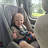 Zaidyn is registered to the contest to win money with this photo: toddler, child, car_seat, vehicle_interior, smile, safety_harness, window, greenery, thumbs_up, seatbelt, happy, young_child, casual_clothing, daylight, car, portrait, baby, seat, transportation, infant